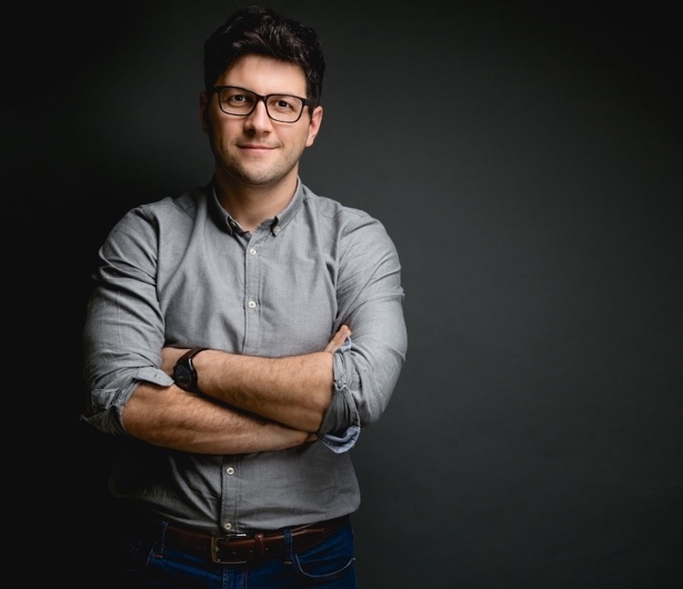 Freundlicher Mann mit verschränkten Armen blickt einen direkt an