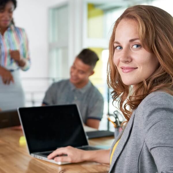 Frau am Schreibtisch mit Team im Hintergrund